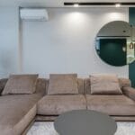 Nowoczesny salon z dużą sofą i okrągłym lustrem nad nią