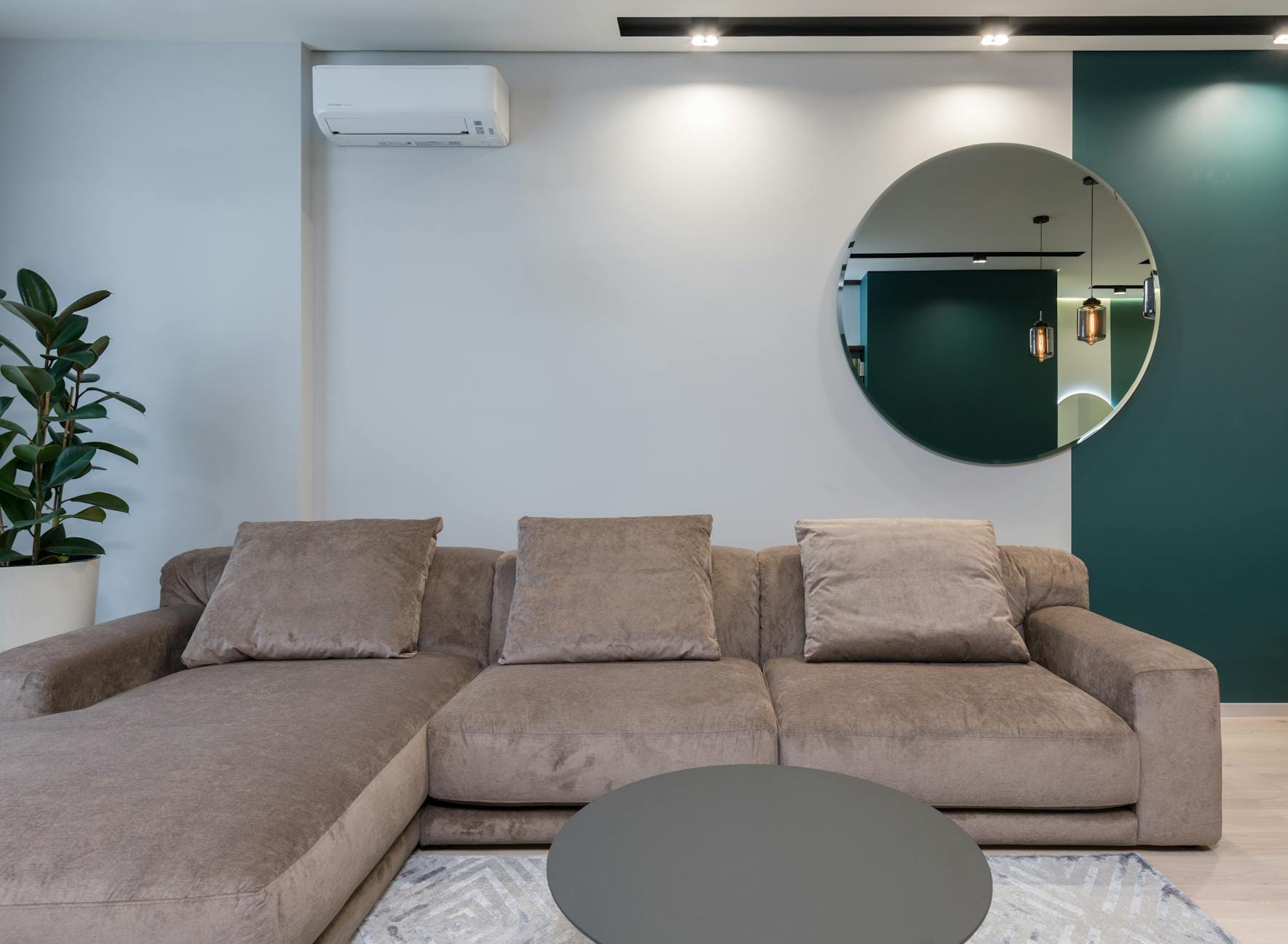 Nowoczesny salon z dużą sofą i okrągłym lustrem nad nią