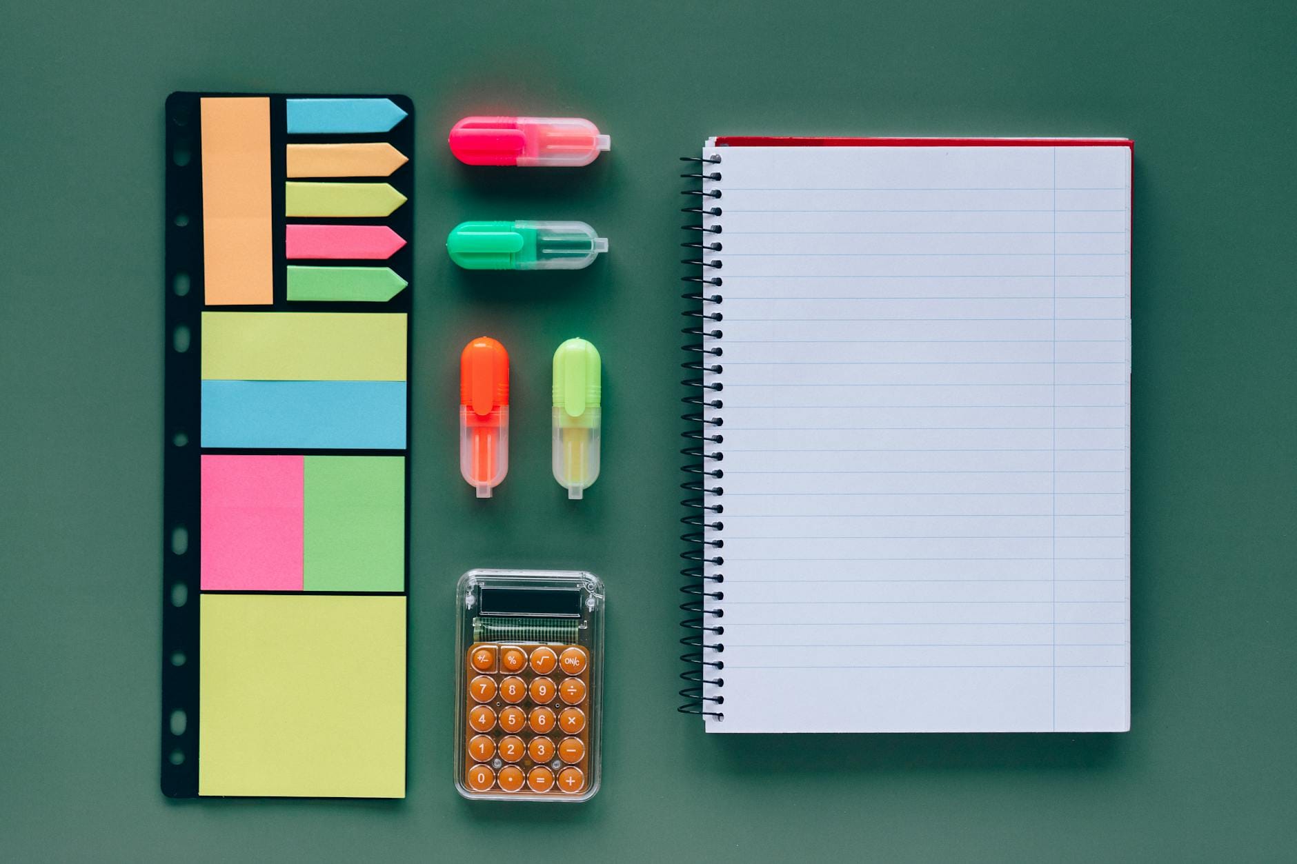 Przybory szkolne z zeszytem i kalkulatorem na zielonym tle