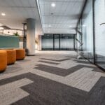 Nowoczesny korytarz biurowy z geometryczną wykładziną i fotelami
